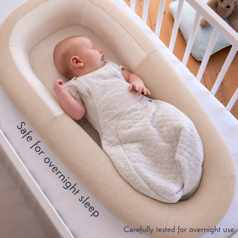 Sleeping baby in the purflo Sleep Tight Baby Bed in Summer Sand, placed inside a white cot.